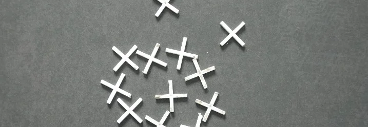 Mehrere weiße Fliesenkreuze auf grauem Grund